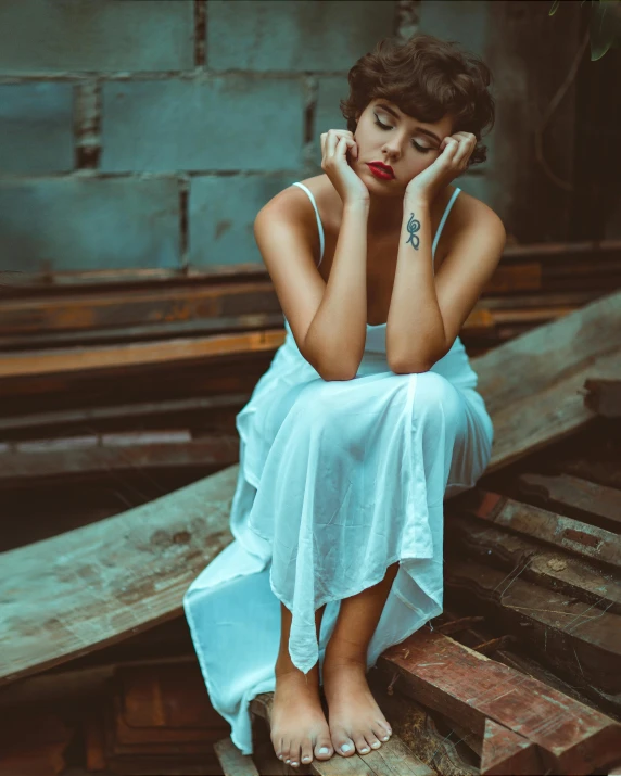 a woman is wearing a blue dress while she sits on a bench