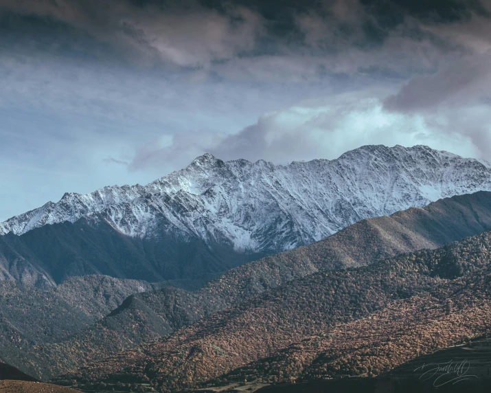 a view of a mountain range under dark cloudy skies