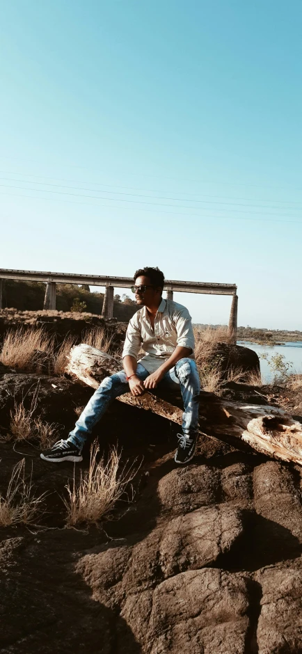 a man sitting on a log by the water