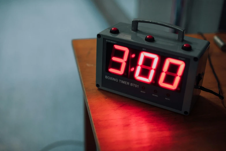 a digital clock sits on top of a wooden table