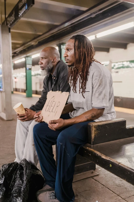 two people sit side by side on a bench at an airport