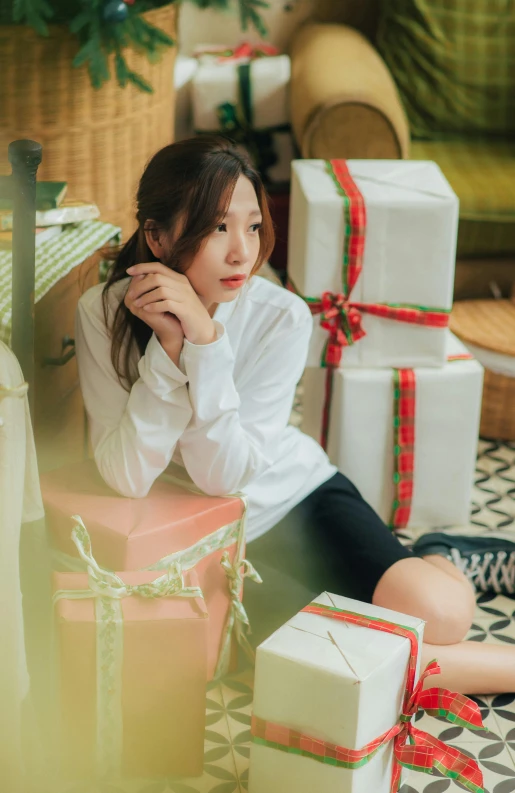 a woman sits on a floor next to wrapped presents