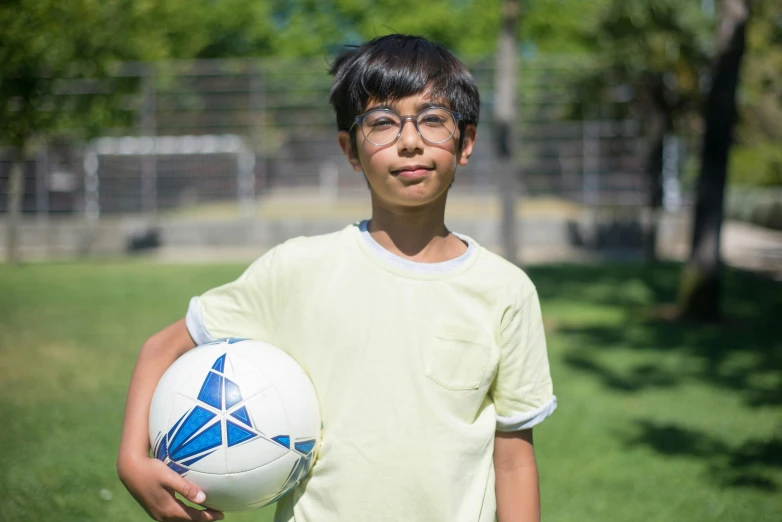 boy with ball in a grassy area near trees