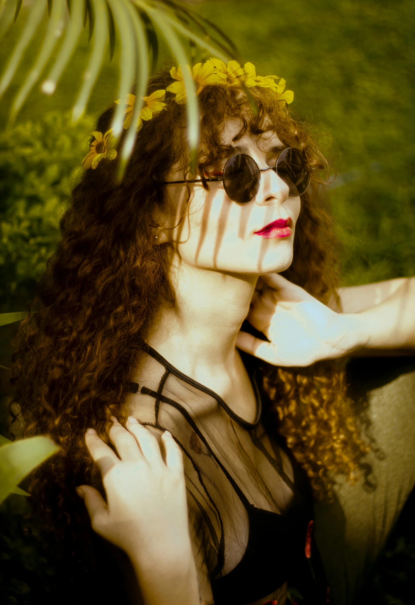 a beautiful young woman in sunglasses standing near bushes