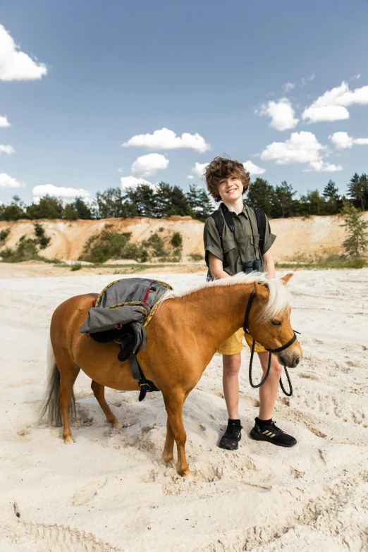 a boy poses for the camera while riding a horse