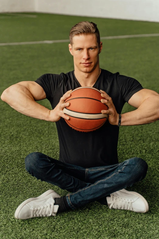 a man sitting on the ground with a basketball in his hand