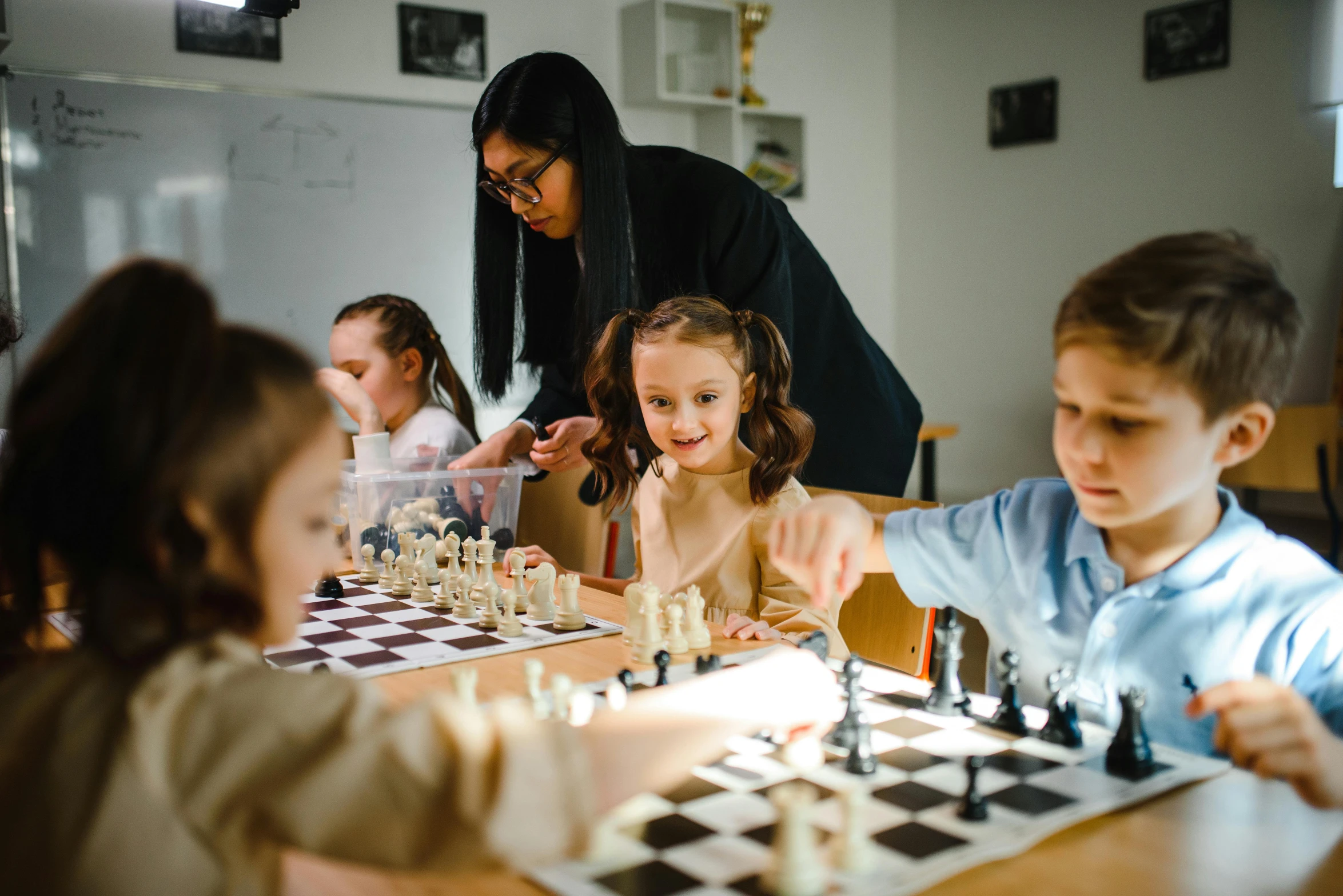 an adult teaching children how to play chess