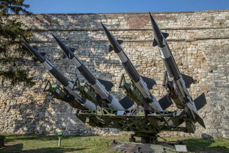 a bunch of large guns are near an old stone wall