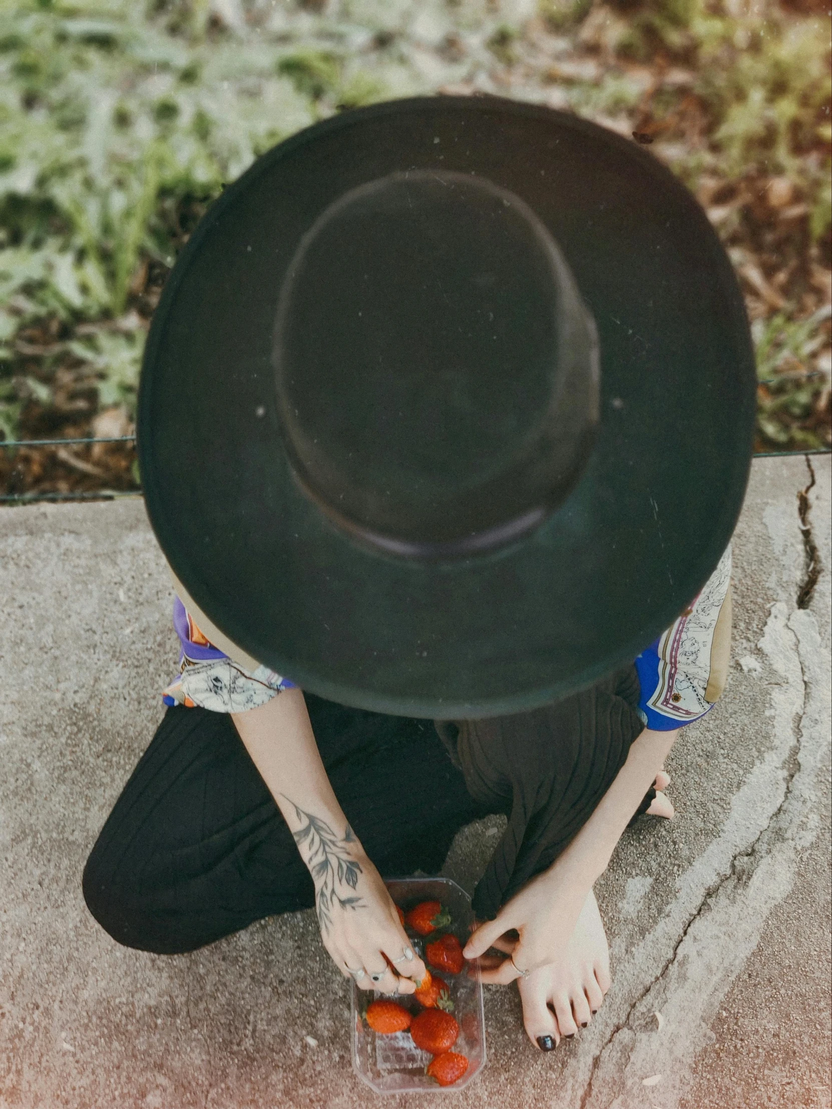 a person sitting on concrete with their hand under the ground