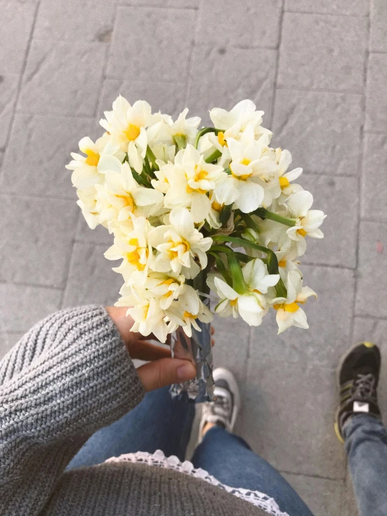 a person is holding some pretty flowers in a vase