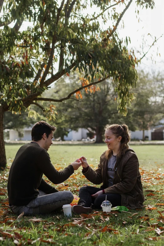 two people are sitting on the grass together, smiling