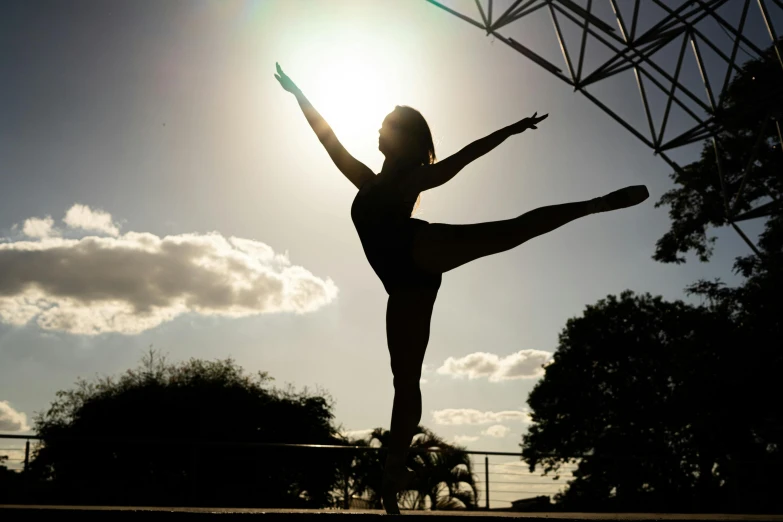 silhouette of person dancing in park at sunset