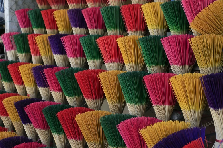 large collection of colorful brooms on a rack