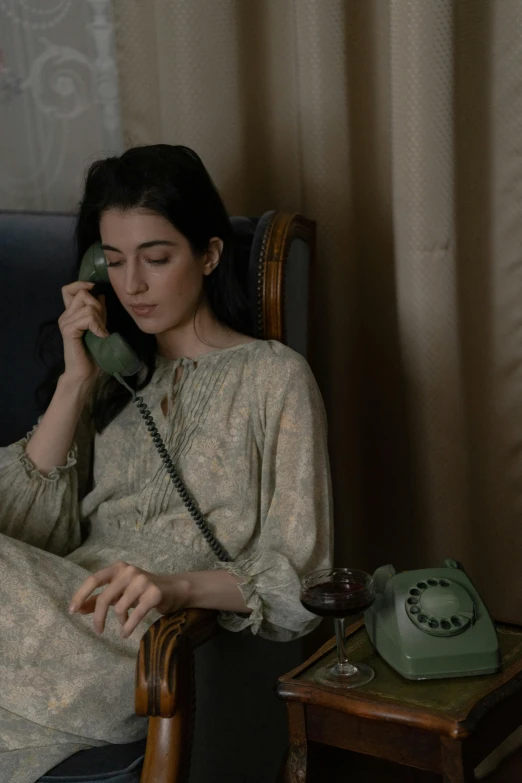 a woman sitting in a chair holding up a telephone