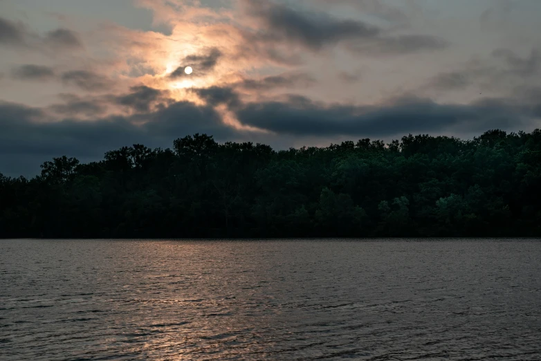 the sun is shining through some clouds near water