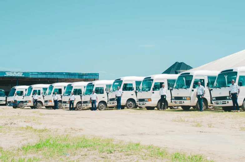 a line up of city busses parked on a dirt road