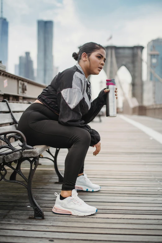 a young woman holding up her arm and sitting on a bench