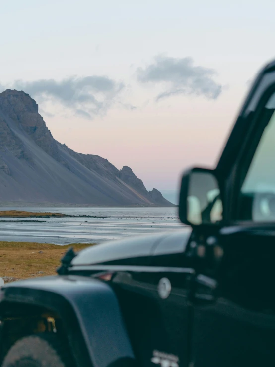 an suv is parked near mountains and water