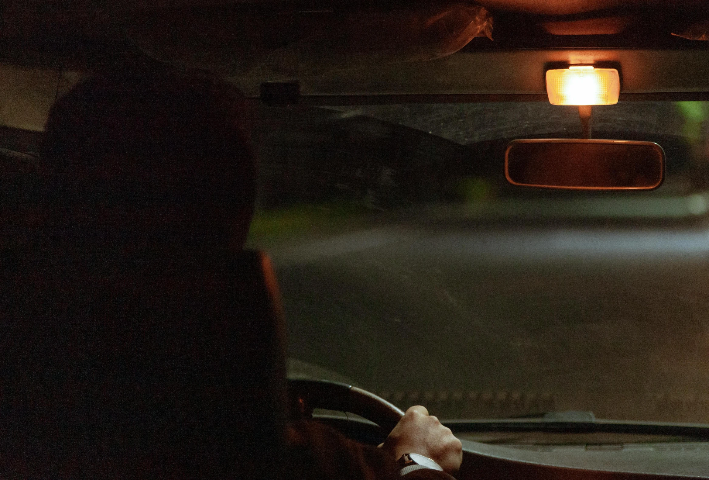 the front view of someone sitting in a car in a night time scene