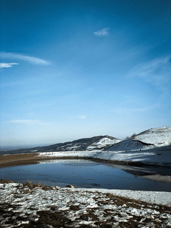 a very small lake surrounded by snow on the side