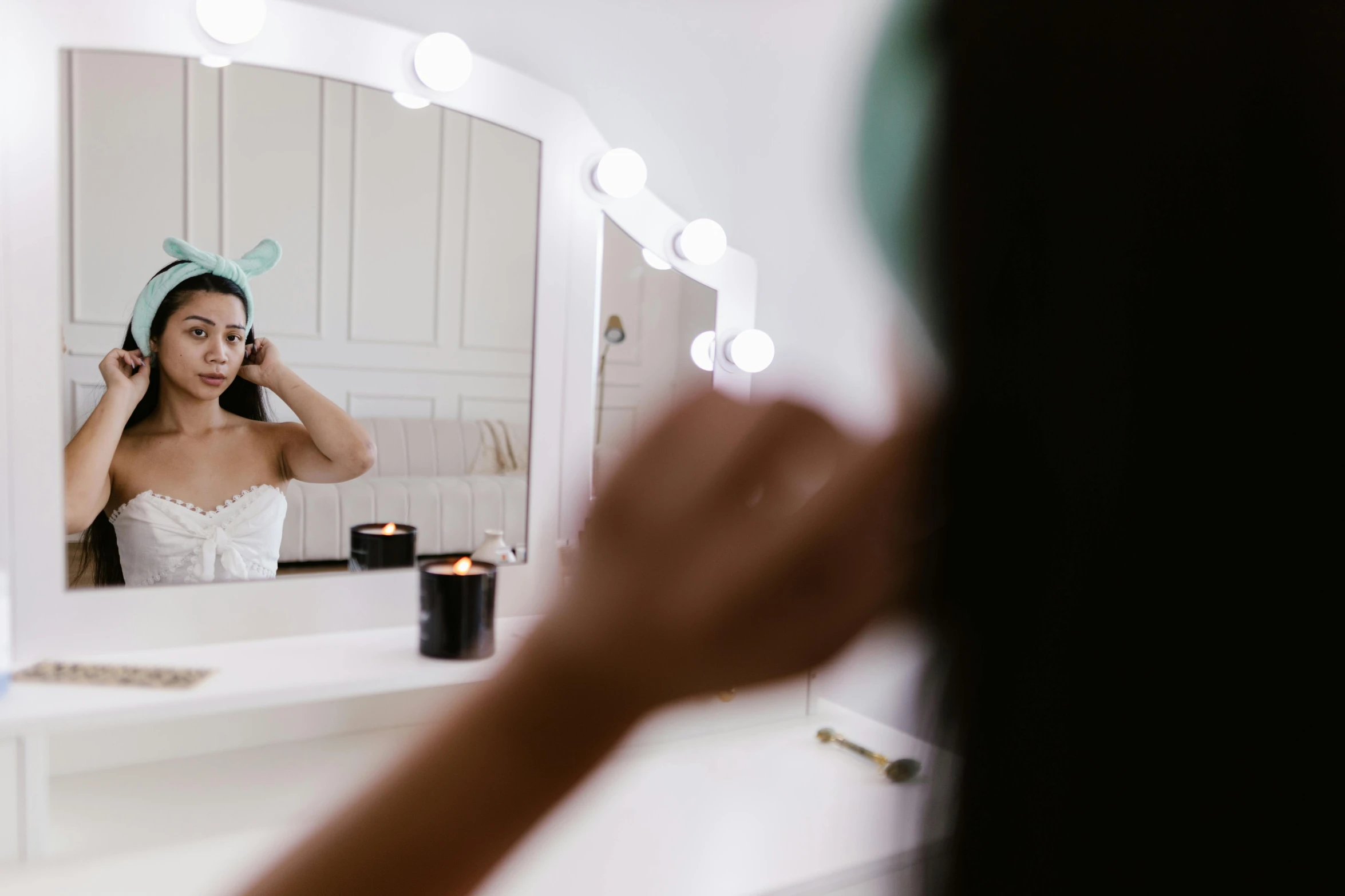 woman in white top brushing her hair in front of mirror