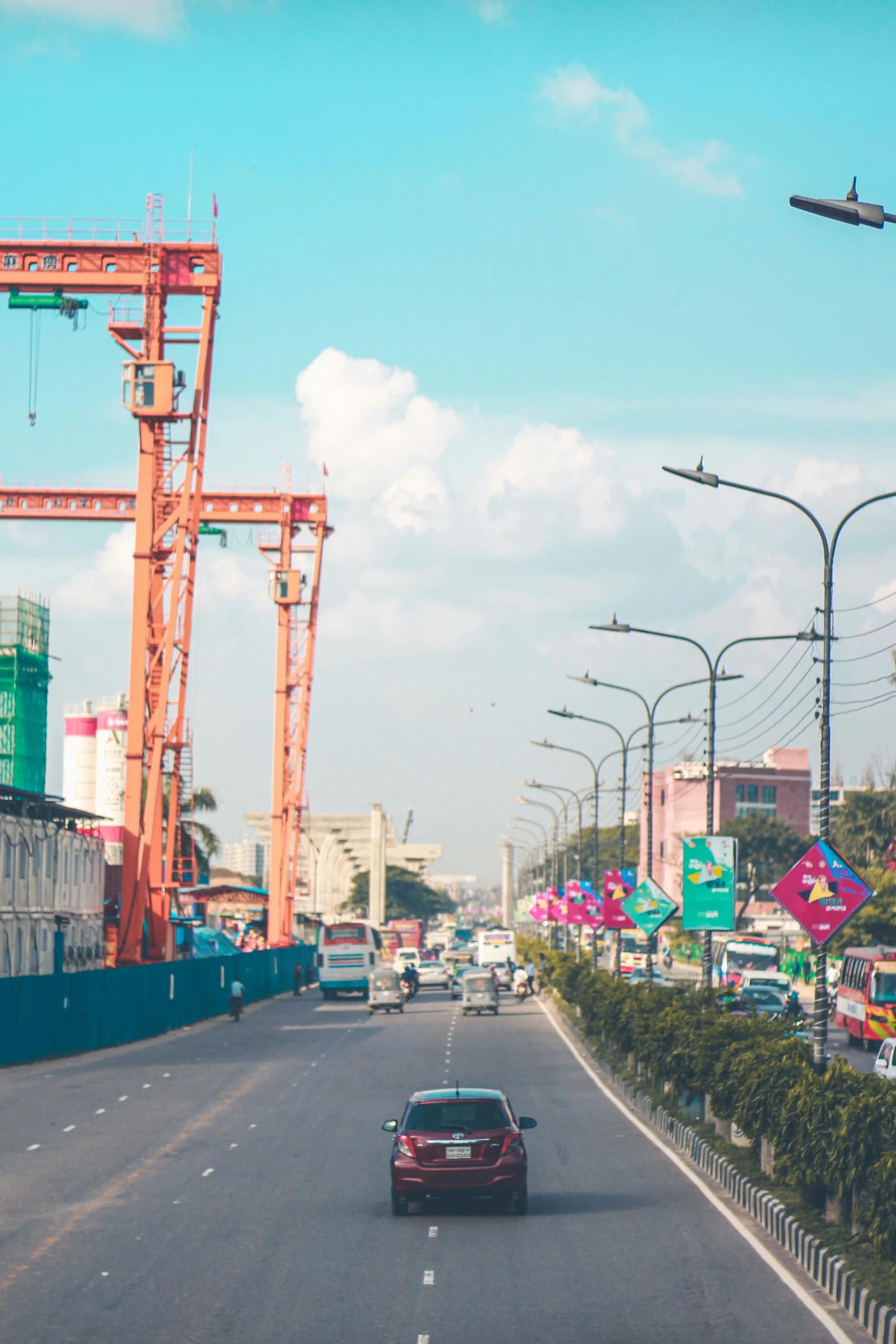 a car driving through an orange construction cranes