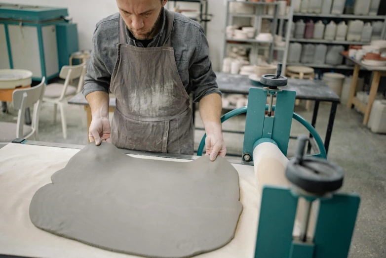 a man wearing an apron making soing grey on a metal surface