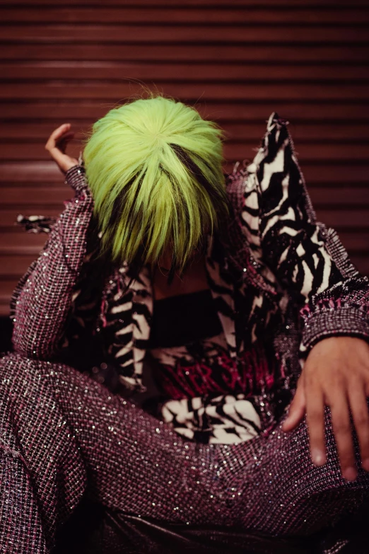 a person with neon green hair is holding up his arm