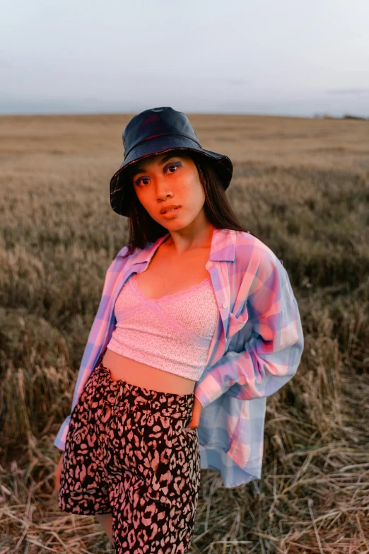 a woman wearing a pink and purple shirt is standing in the grass