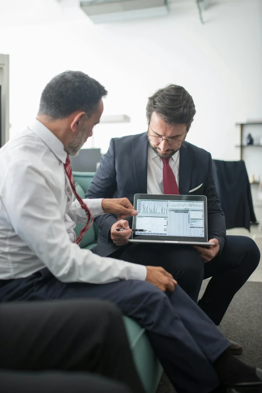 two men looking at an ipad with blue prints on it