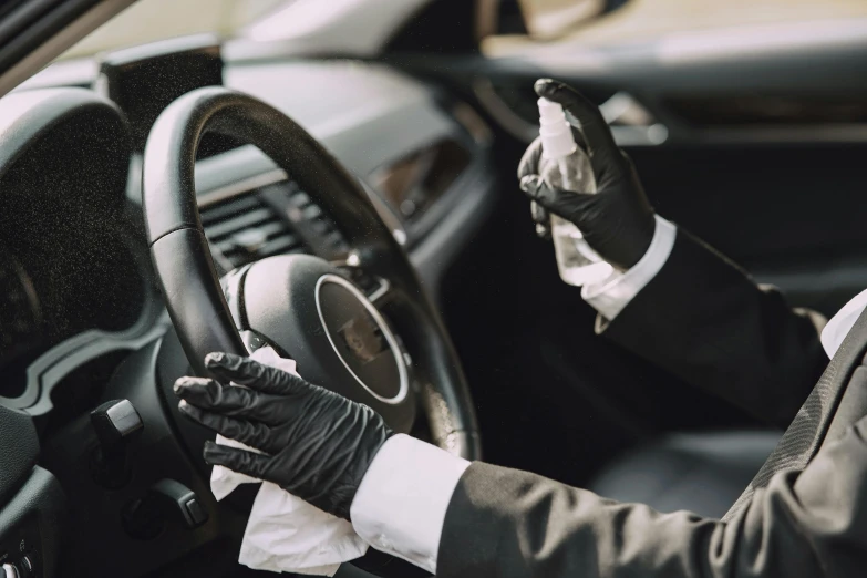 a person with black gloves on sitting at a steering wheel