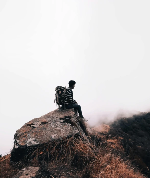 a person with a hat sitting on a rock