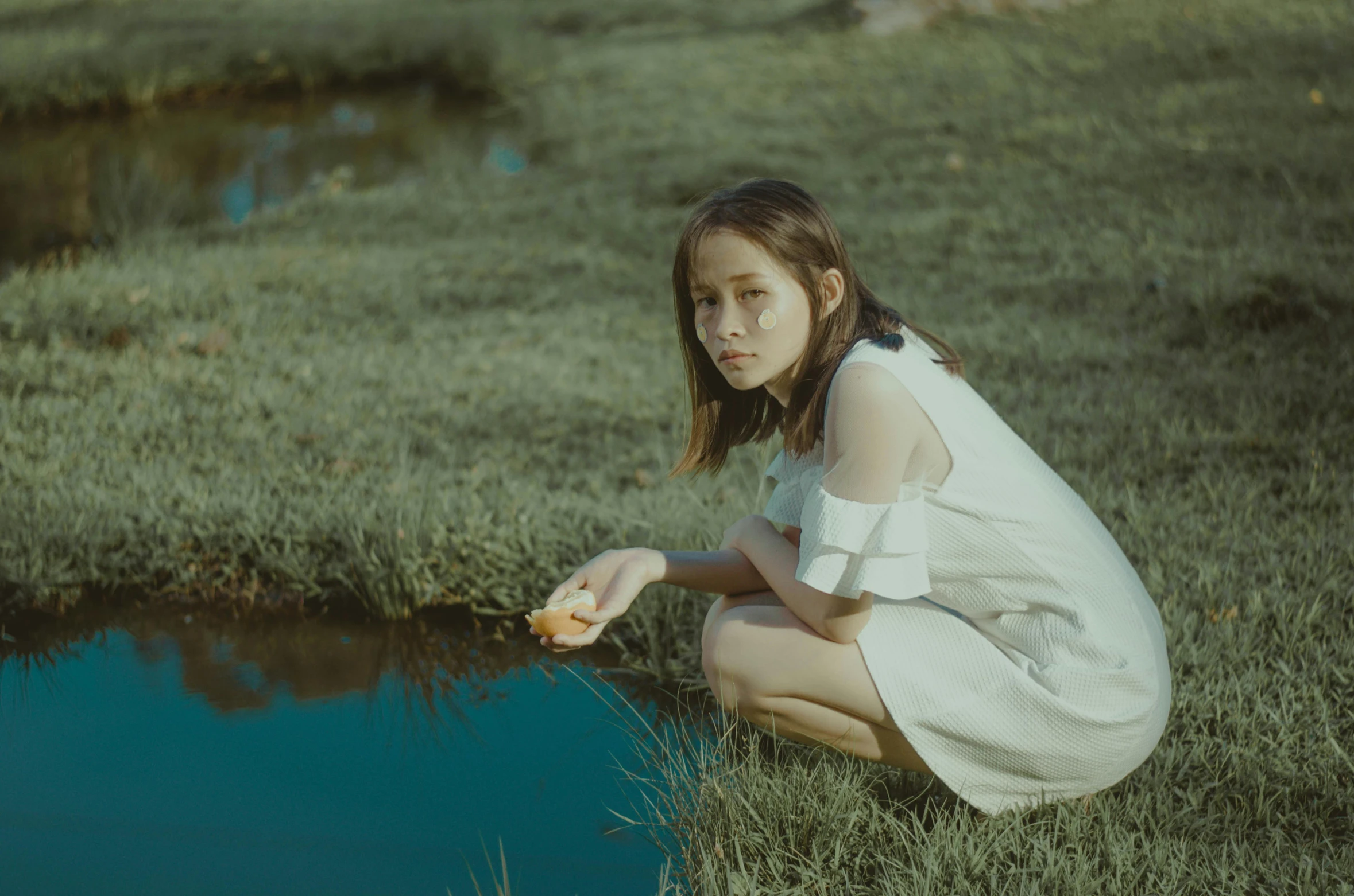 a woman kneeling down on grass next to a dle