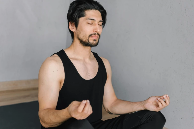 a man with black hair is sitting in yoga pose