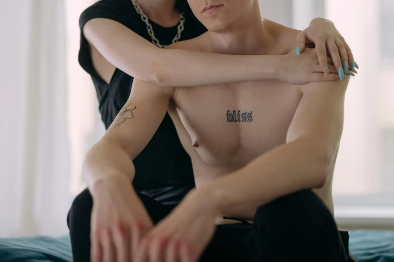 a shirtless man sitting next to another woman