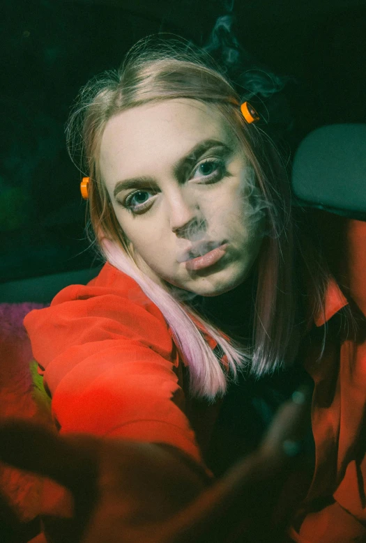 a young blonde woman smoking and looking into the camera