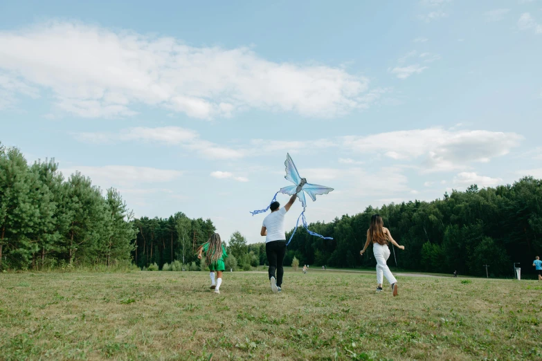 adults, children and dog are flying kites in a grassy field