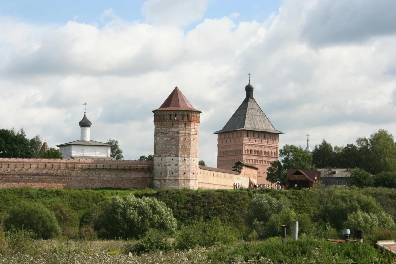 three tall brick towers with a green field below