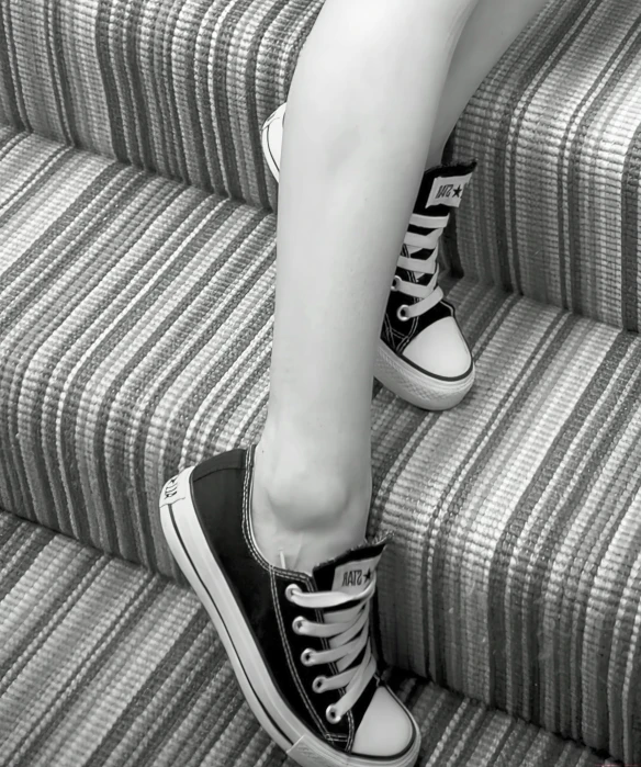 black and white pograph of woman's legs sitting on stairs