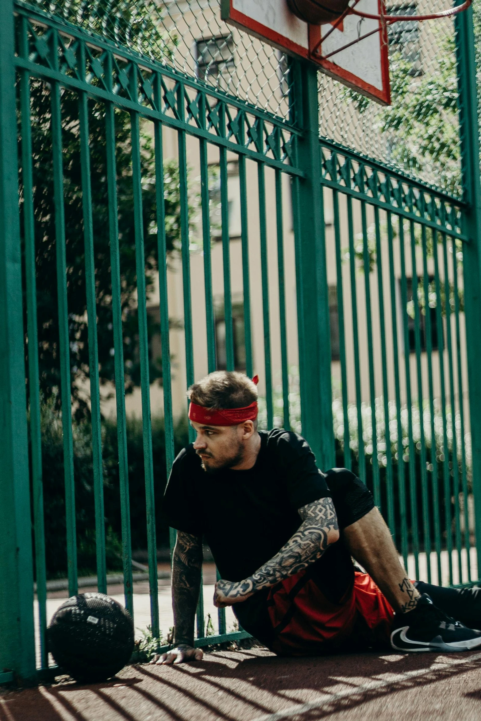 a man sitting in front of a basketball hoop with his hands near his mouth