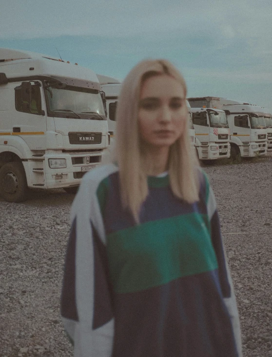 a woman standing in front of a bunch of large trucks