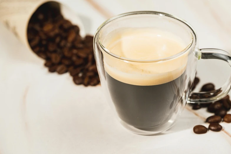 a glass mug filled with liquid surrounded by coffee beans