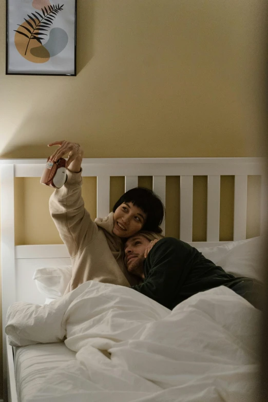 two women are lying in bed smiling at the camera