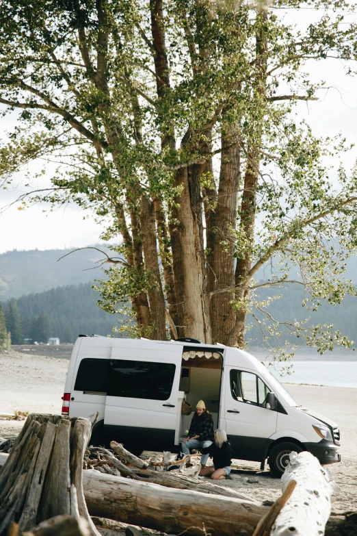 a camper van sits in the woods near the water