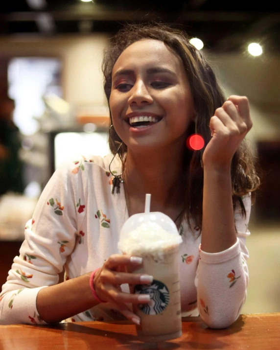 a girl smiling at the camera while drinking a starbucks drink