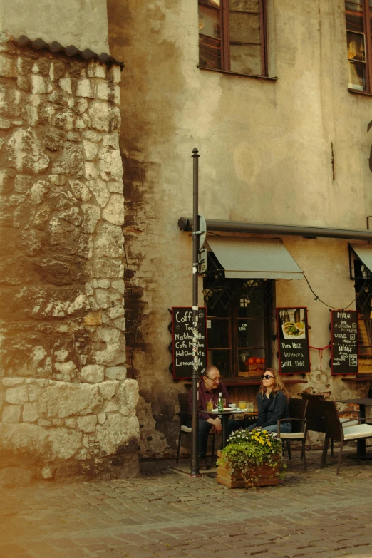 two people are sitting in an outdoor cafe