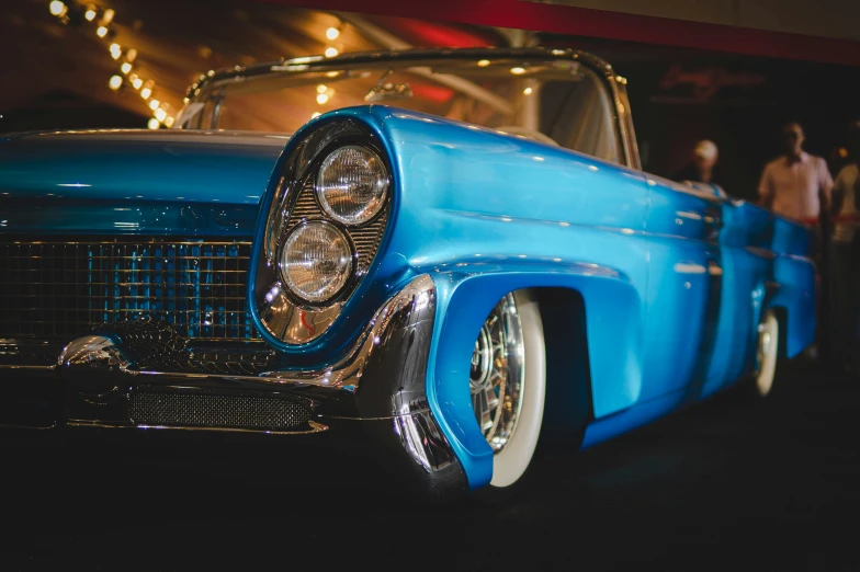 a classic blue car is parked in front of other classic cars