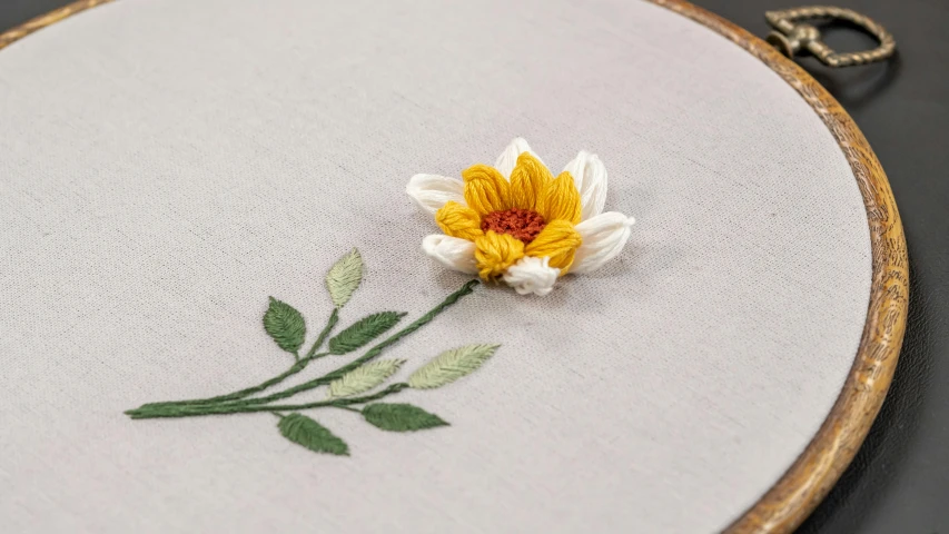 this picture shows a single yellow flower on an embroidered wall hanging