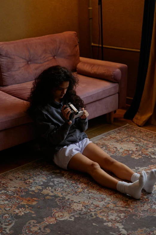 a girl sitting on the floor with a cell phone