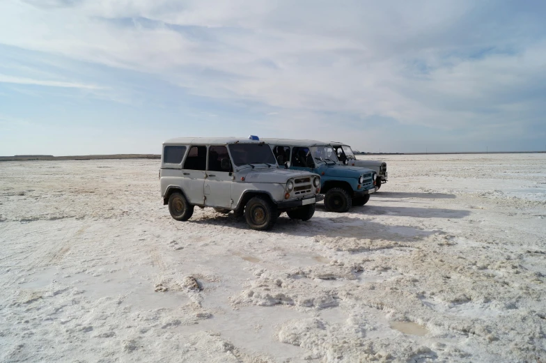 two vehicles parked in the desert by some ice